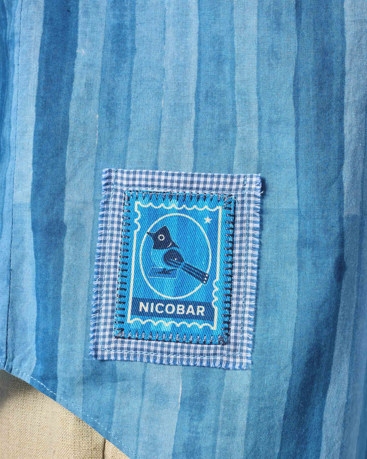 Close-up of a blue bird stamp patch on a Ganga shirt.