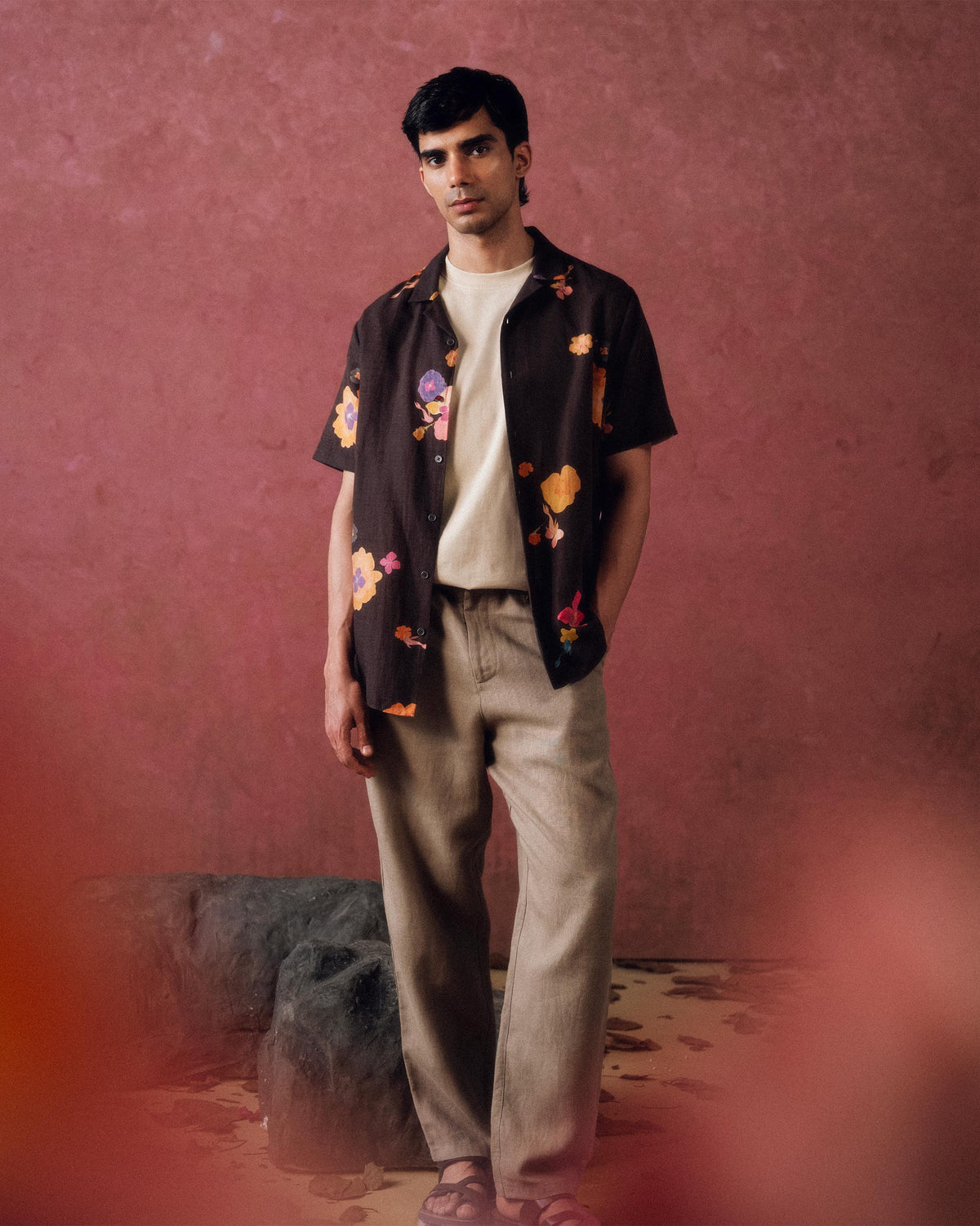 Person wearing an open brown Mistari shirt with orange and pink flowers.