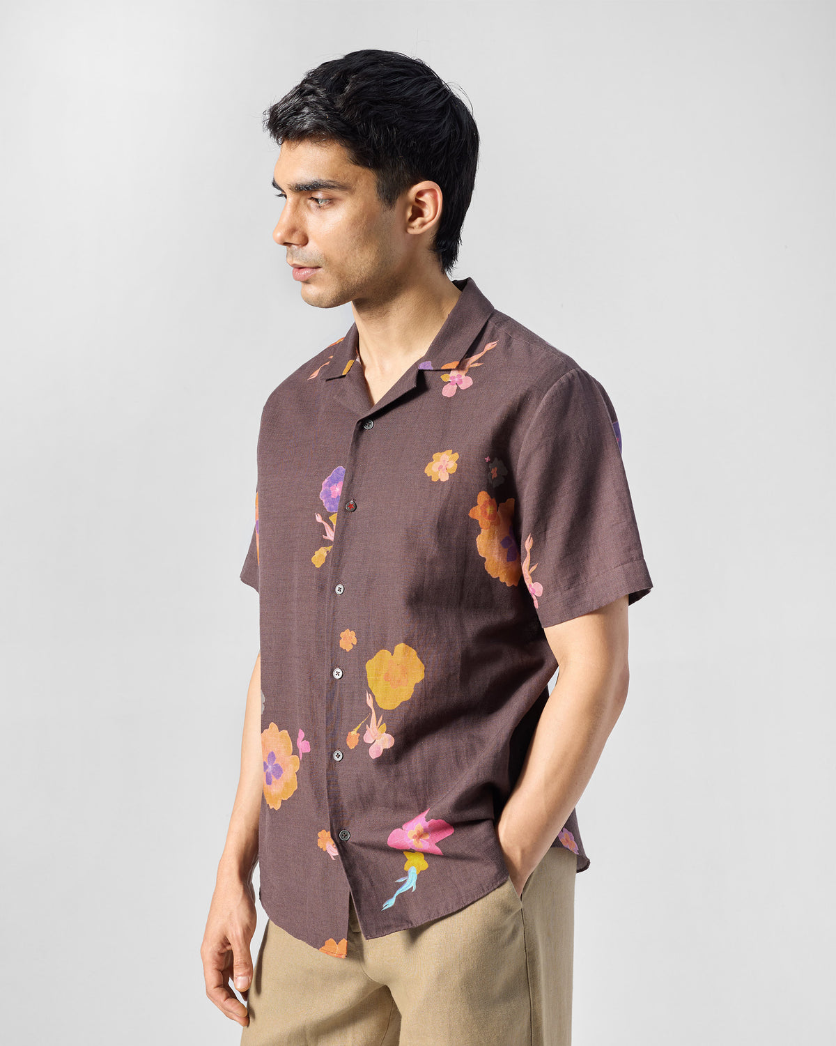 Side view of a brown Mistari shirt with colourful floral print worn by a person.