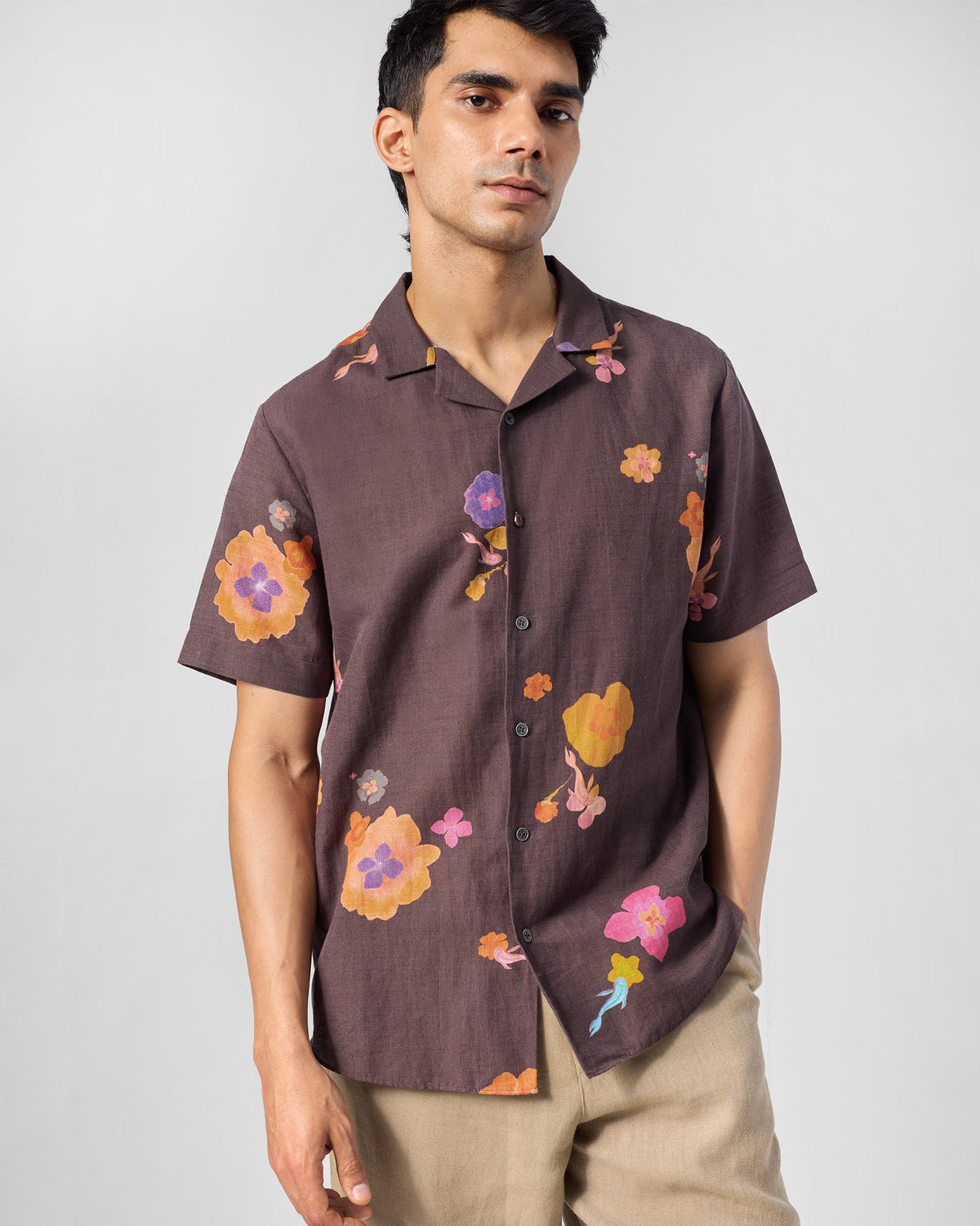 Person wearing a brown Mistari shirt with a camp collar and floral print.