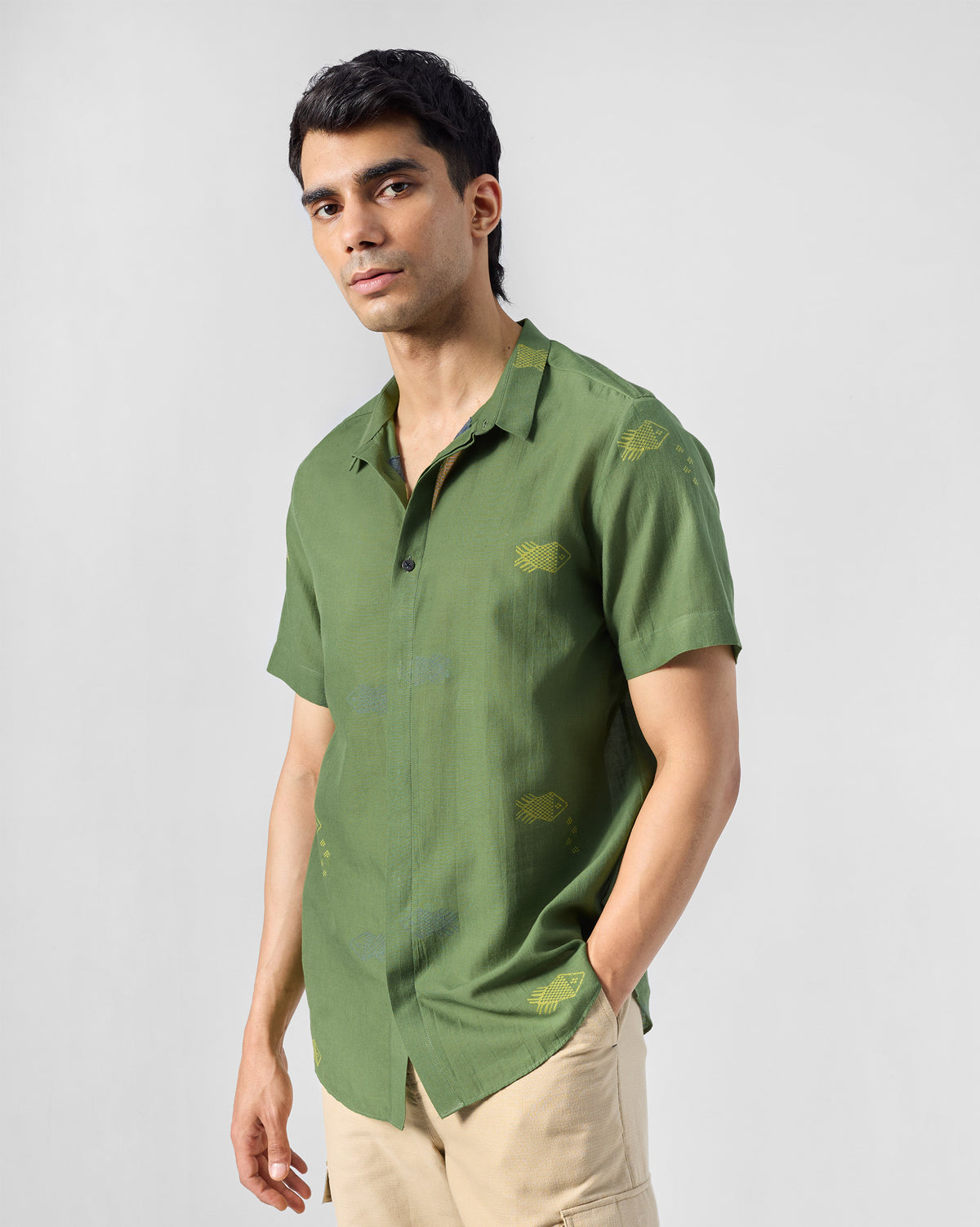 Person wearing a green Riverine shirt with scattered yellow fish motifs.
