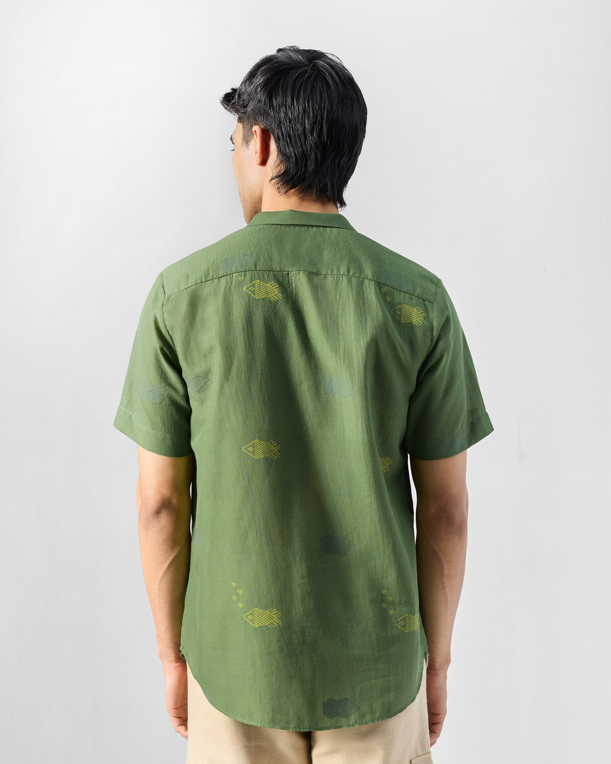 Back of a green Riverine shirt showing scattered fish motifs.