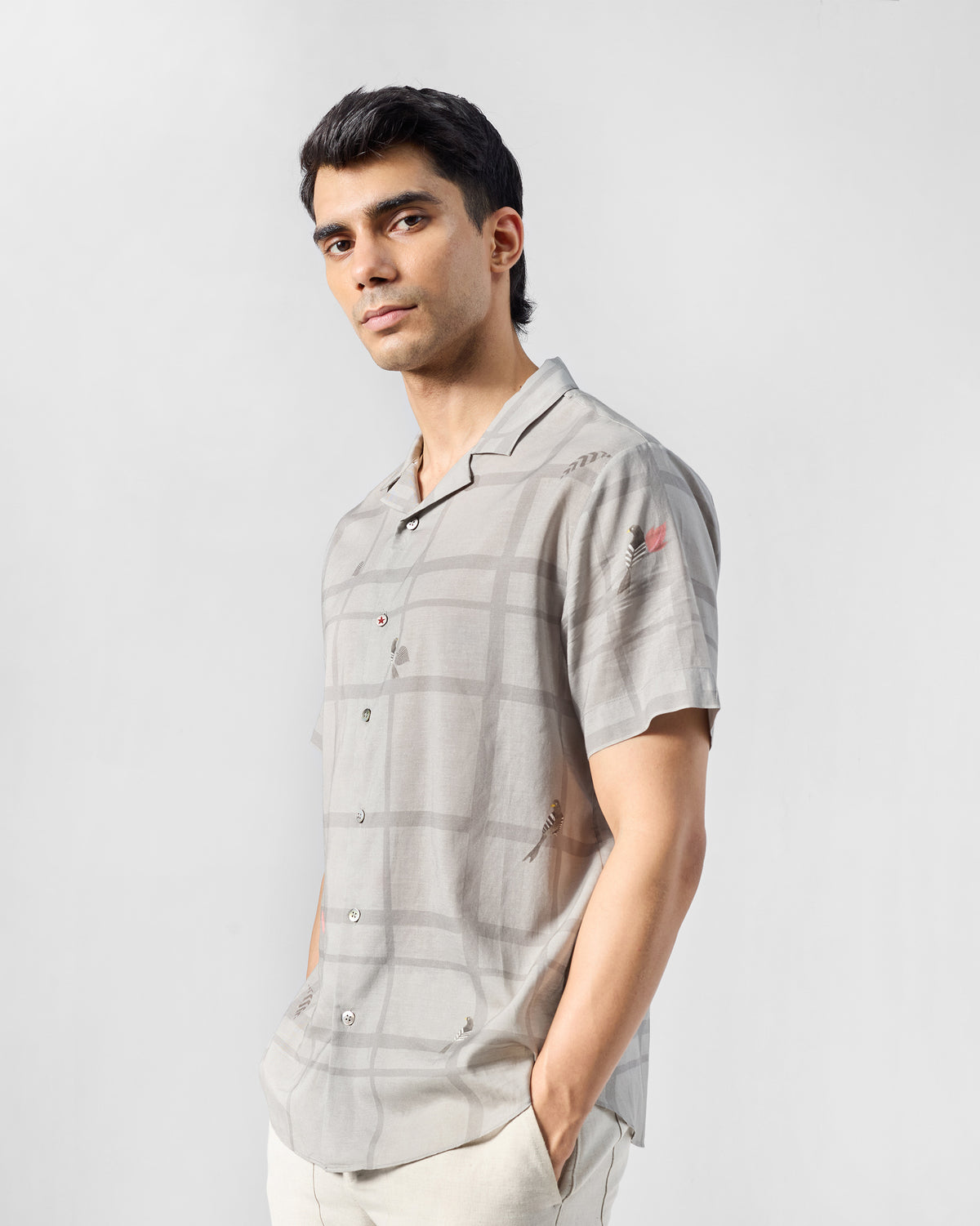 Person wearing a charcoal Mistari Shirt with a bird motif on the sleeve.