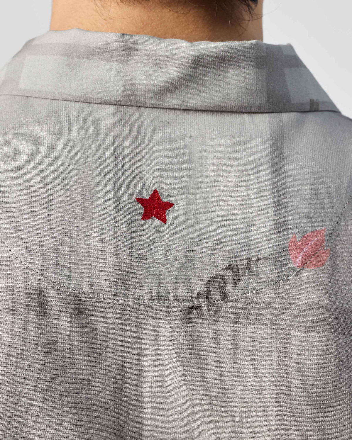 Close-up of a red star on the back of a charcoal Mistari Shirt.