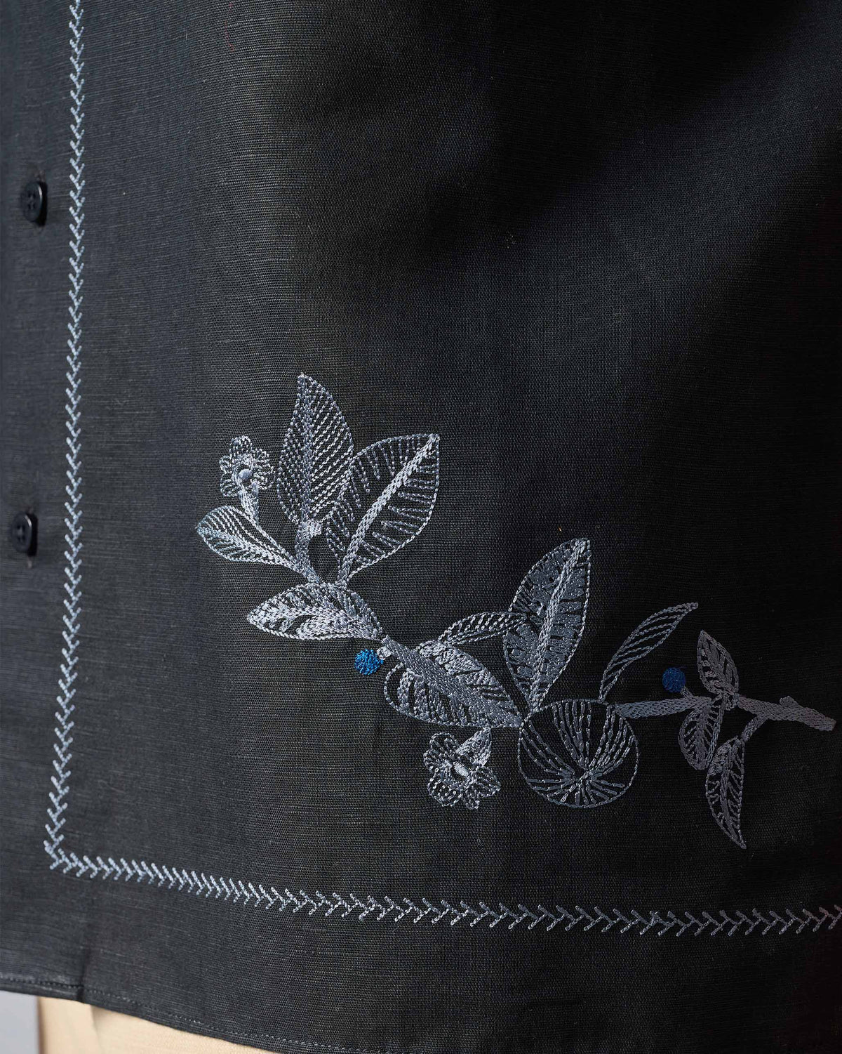 Close-up of leaf embroidery and zigzag hem stitching on a black Delta shirt.