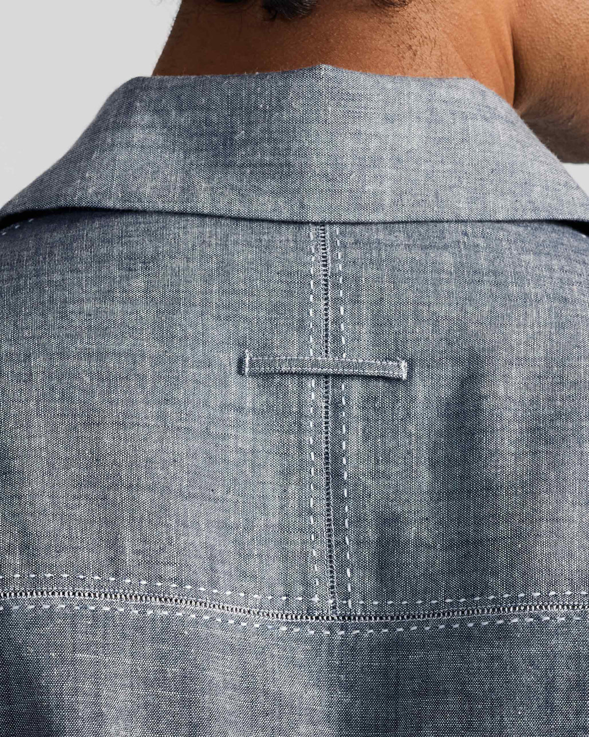 Close-up of the indigo shirt back yoke with white contrast stitching and a small locker loop.