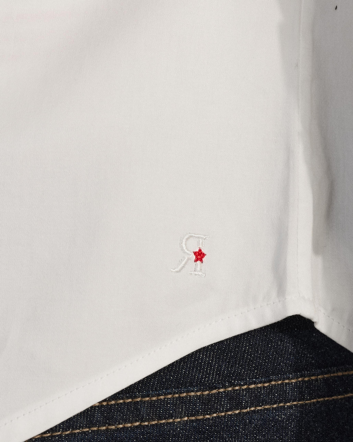 Close-up of a white Badger shirt hem with an R and red star.
