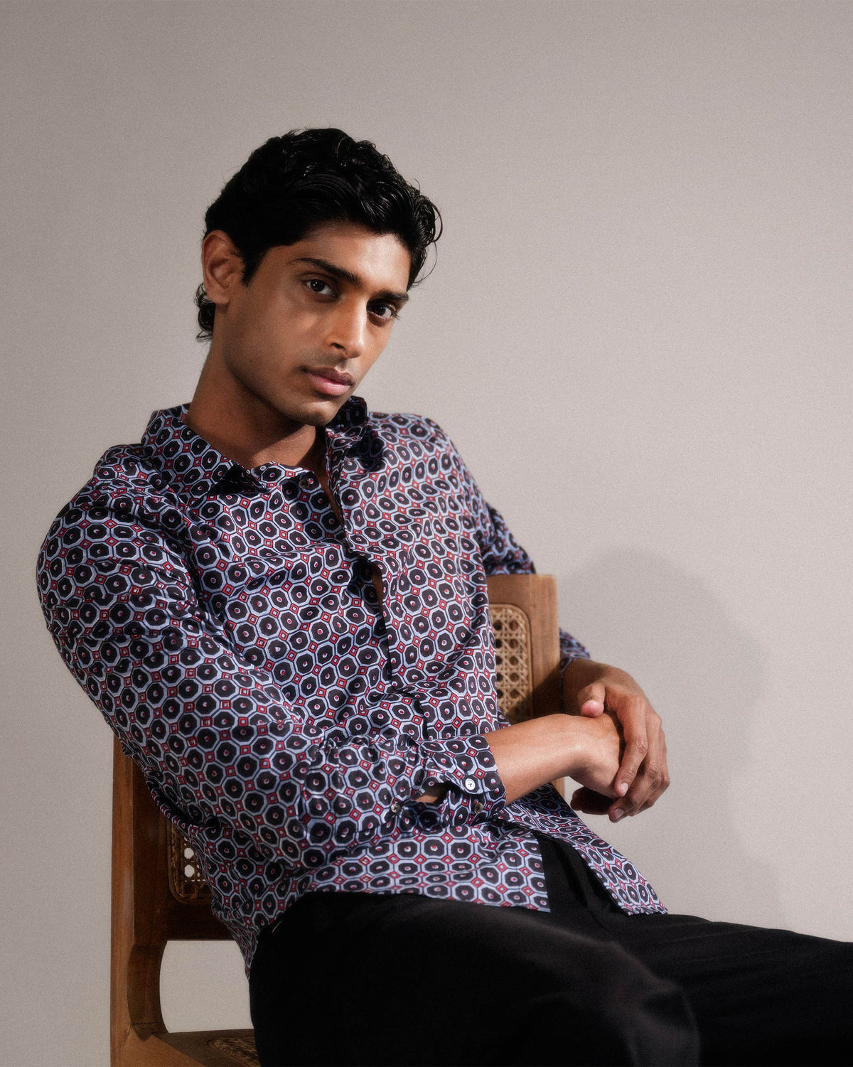 Wood Pigeon Shirt worn seated in a navy geometric print with red accents.