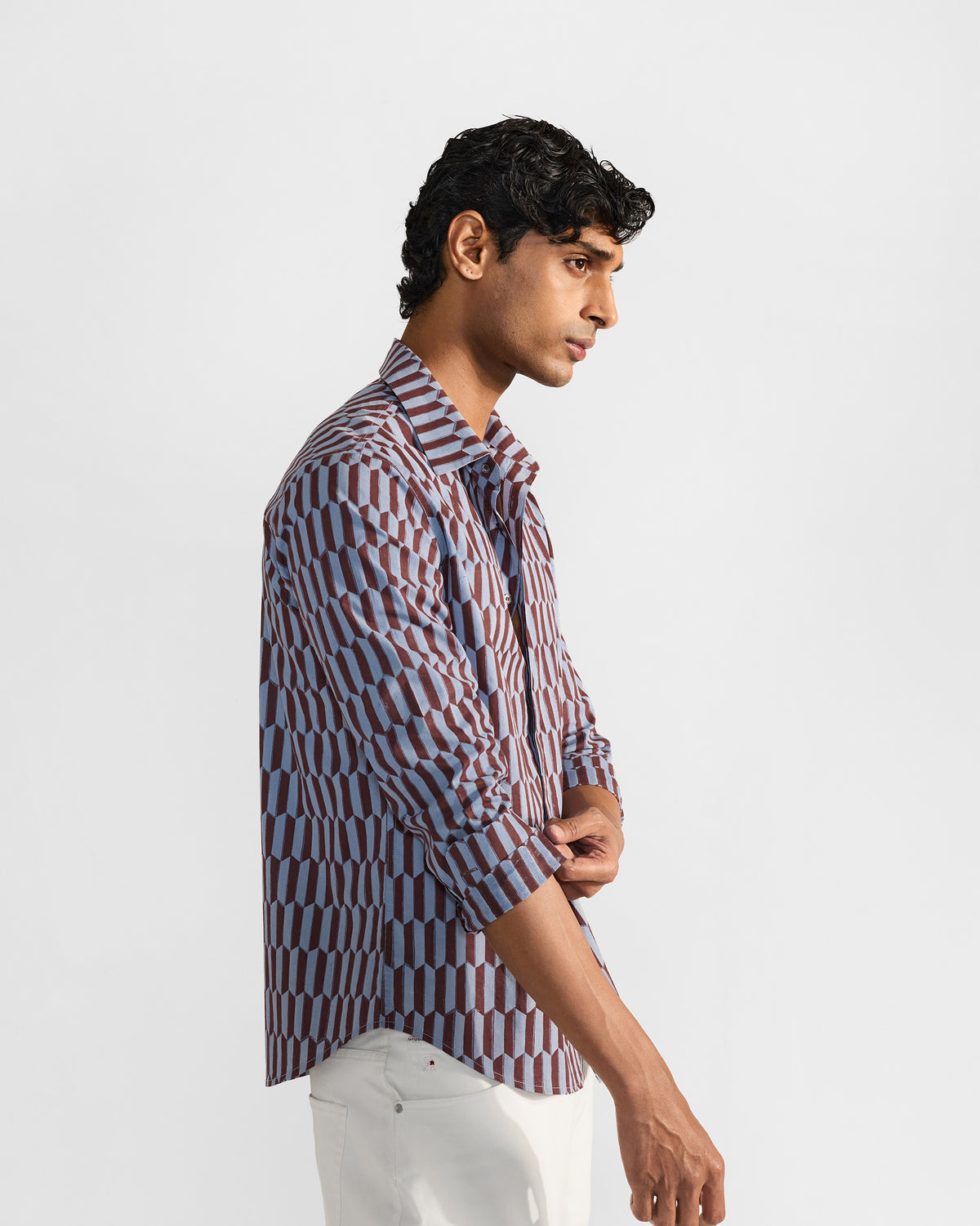 Side view of a brown and light blue geometric print Drongo shirt with a rolled sleeve.