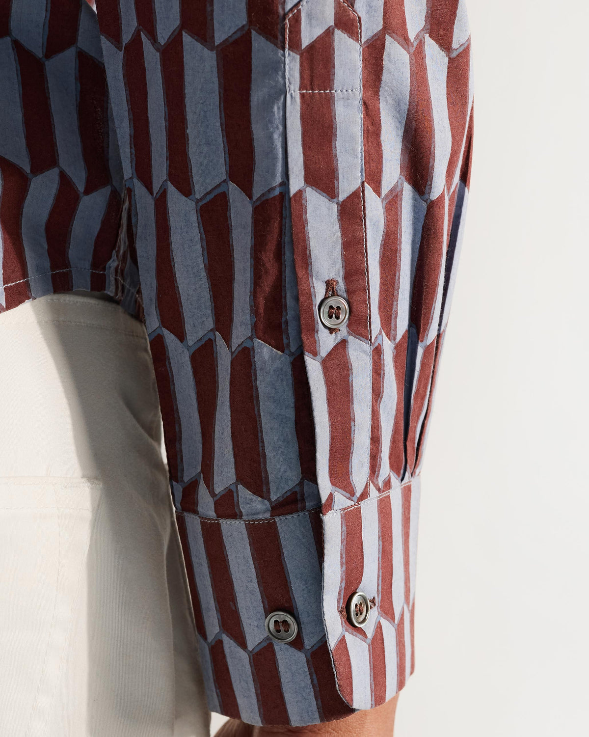 Close-up of the buttoned cuff on a brown and light blue geometric print Drongo shirt.