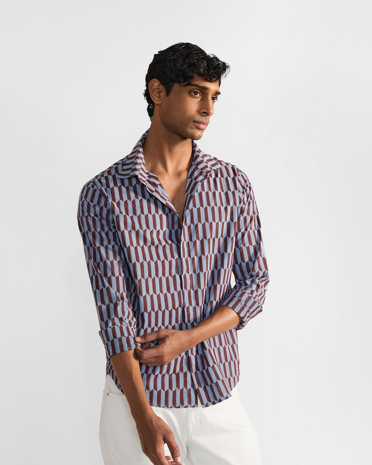 Person wearing a brown and light blue geometric print Drongo shirt with rolled sleeves.