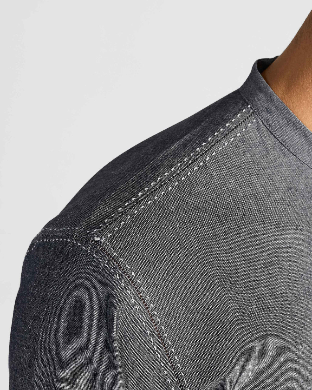 Close-up of white openwork stitching on the shoulder of a charcoal Marten shirt.