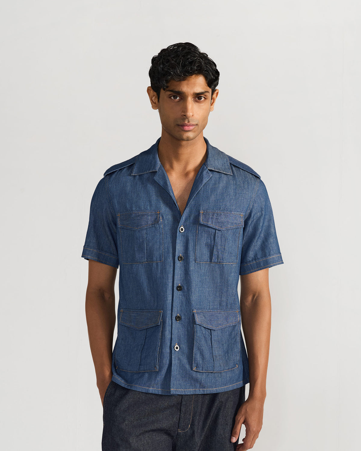Person wearing a blue denim Sambar shacket with four utility pockets.