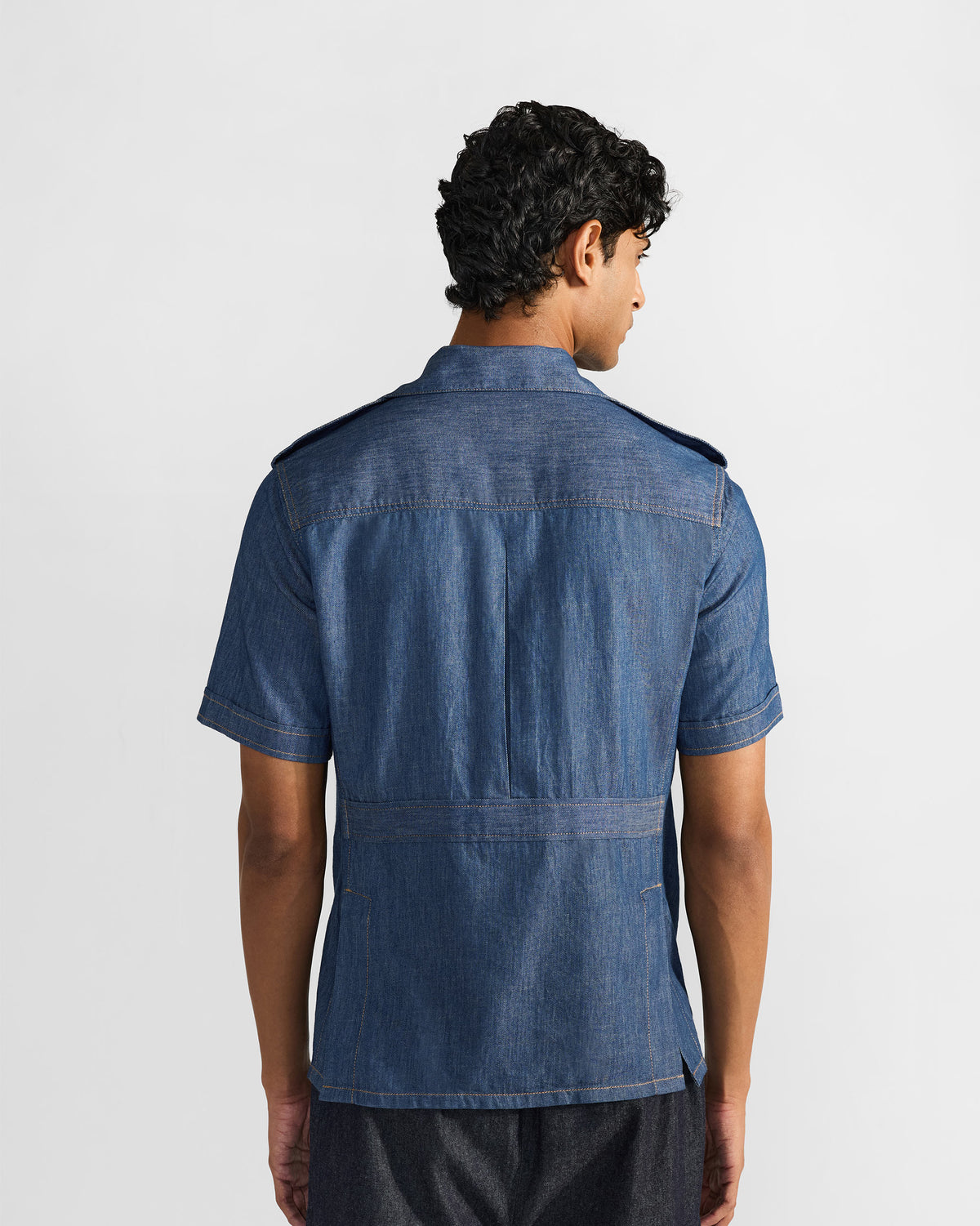 Back of a blue denim Sambar shacket with a box pleat and waist band.