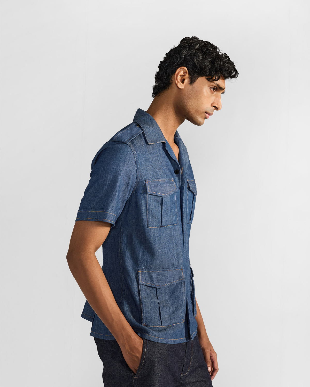 Side view of a blue denim Sambar shacket with flapped utility pockets.