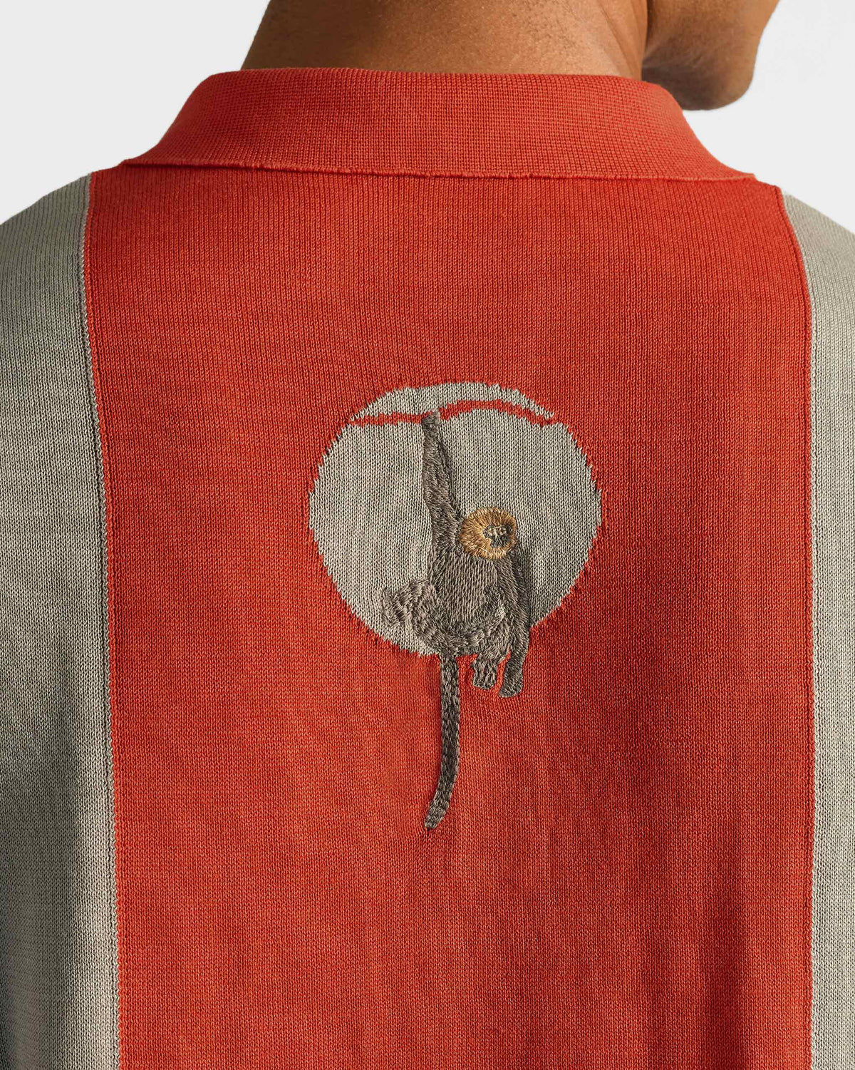 Close-up of Bonnet Polo back graphic of a monkey hanging in a circle.