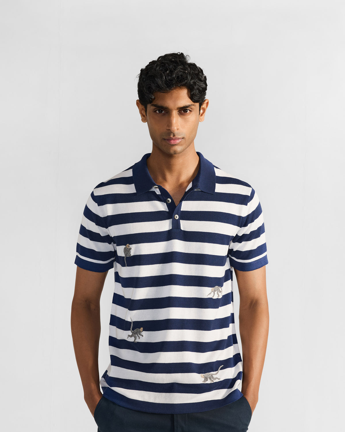 Person wearing a navy-and-white striped polo with embroidered macaques.