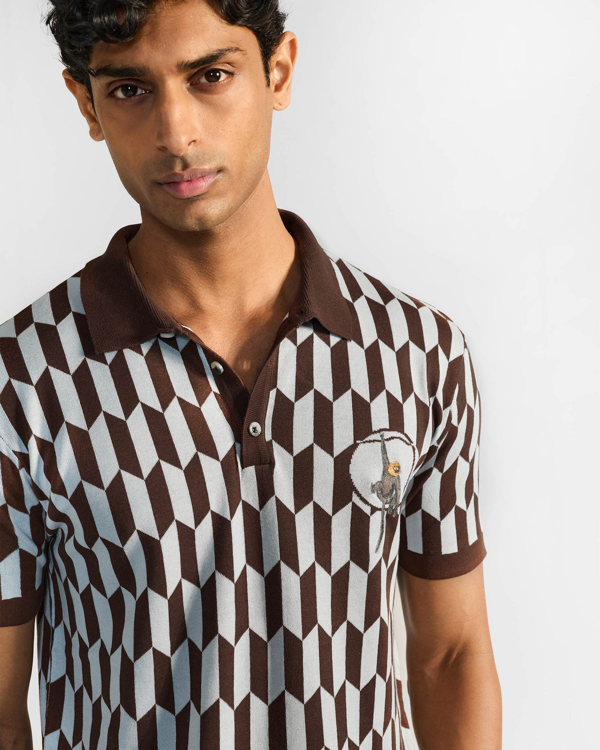 Close-up of a Langur polo showing the chest monkey motif and brown collar.