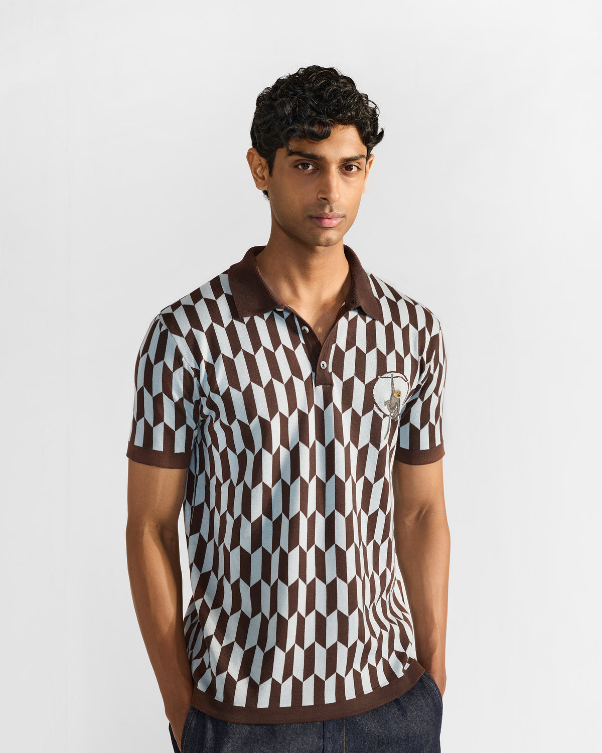 Person wearing a brown and light grey geometric Langur polo with a ribbed hem.