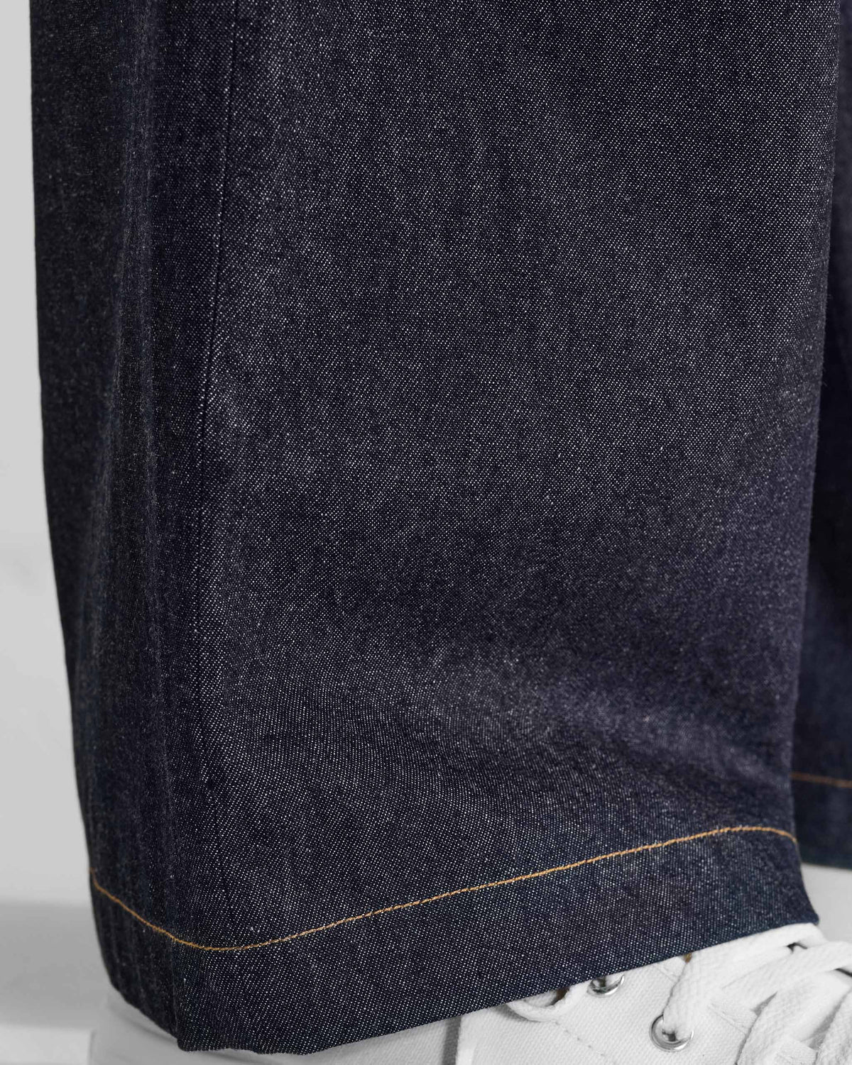 Close-up of the contrast-stitched hem on denim Thrush Trousers.