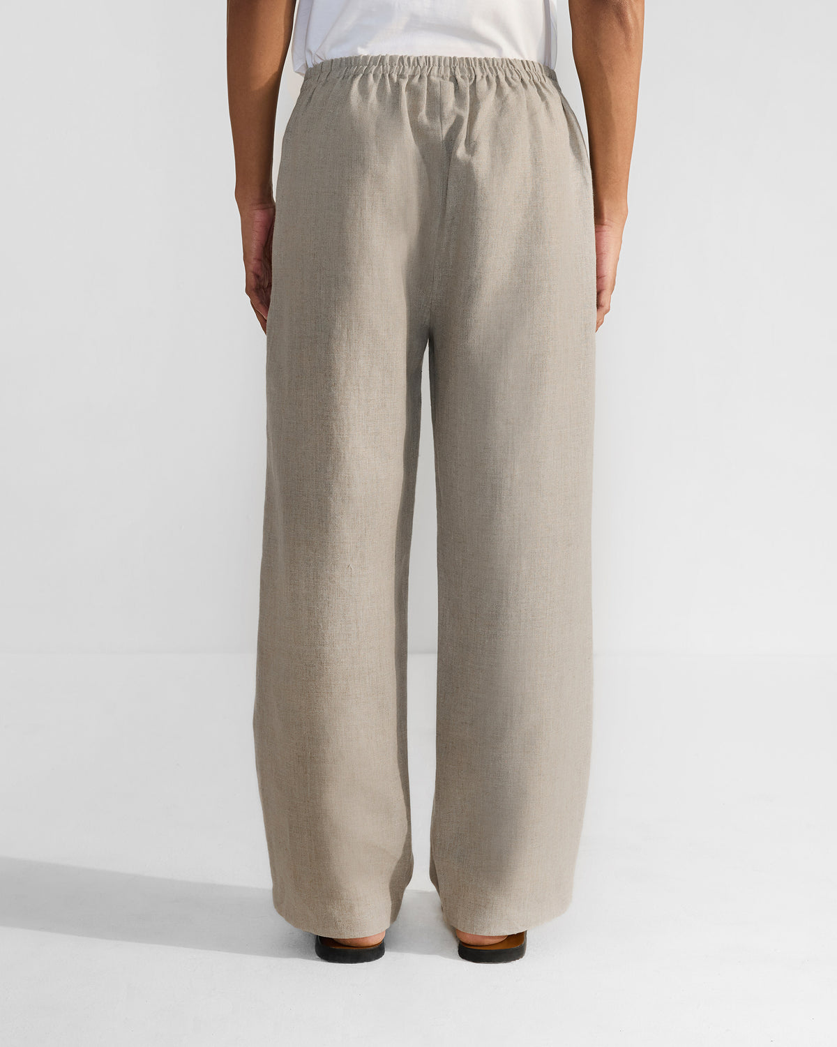 Back of beige Ibex Trousers with an elasticated waistband and wide-leg drape.