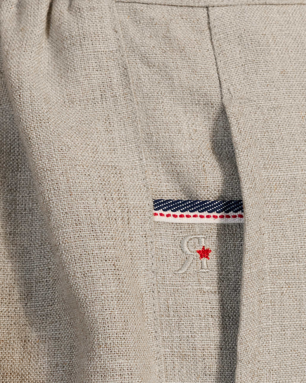 Close-up of beige Ibex Trousers showing a striped pocket tape and red star embroidery.