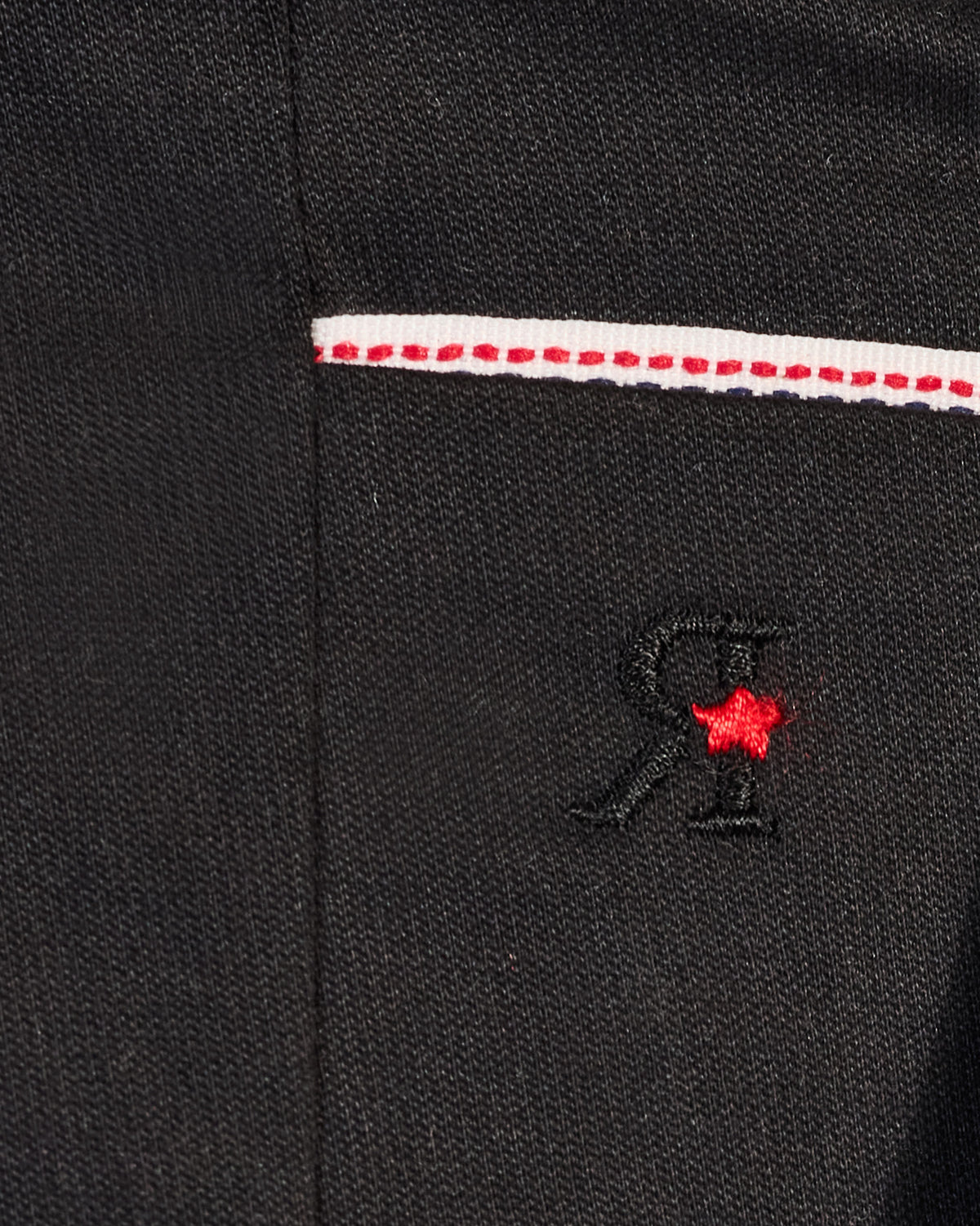 Close-up of black Panther Trousers showing an embroidered R and red star.