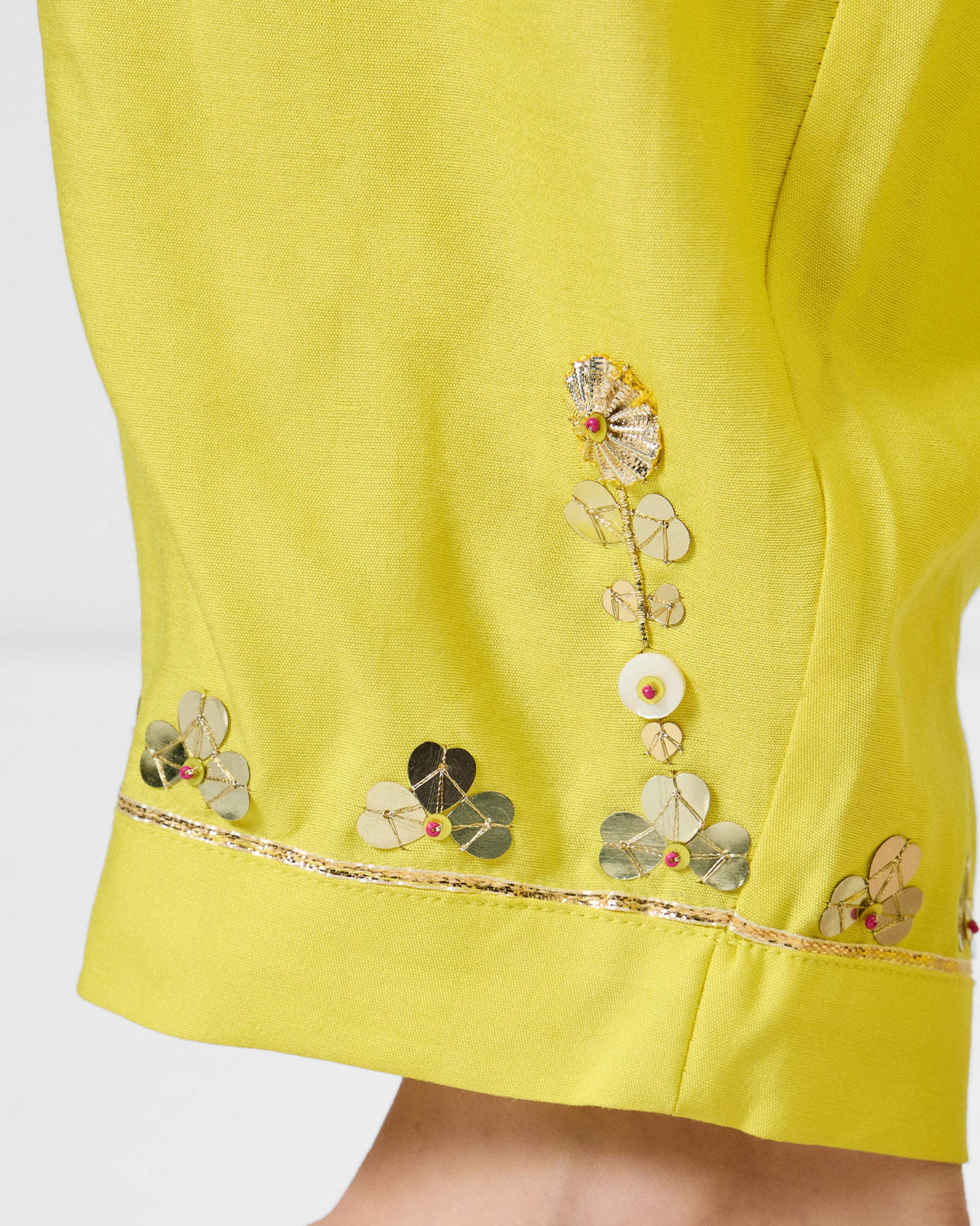 Close-up of gold sequin embroidery on yellow Lebong pant hems.