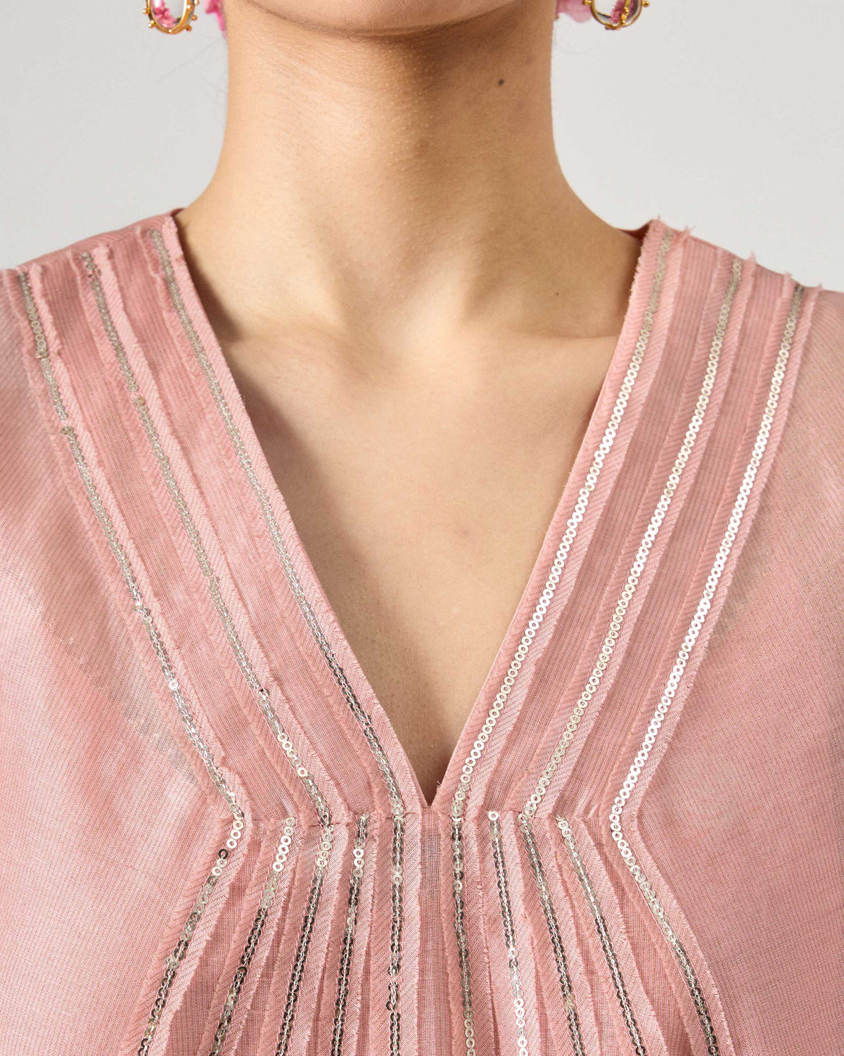 Close-up of silver sequin lines at the V-neck of a pink embroidered Sukhna kurta.