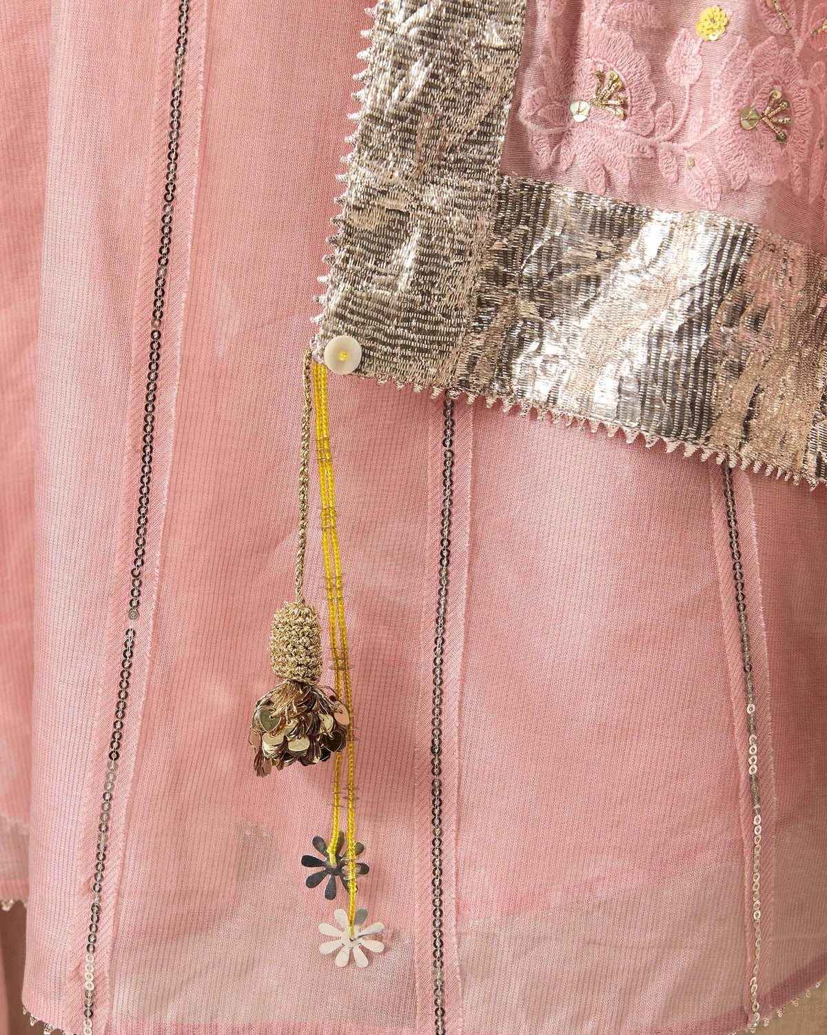 Close-up of dust pink Lila dupatta embroidery with a silver border and yellow tassel.