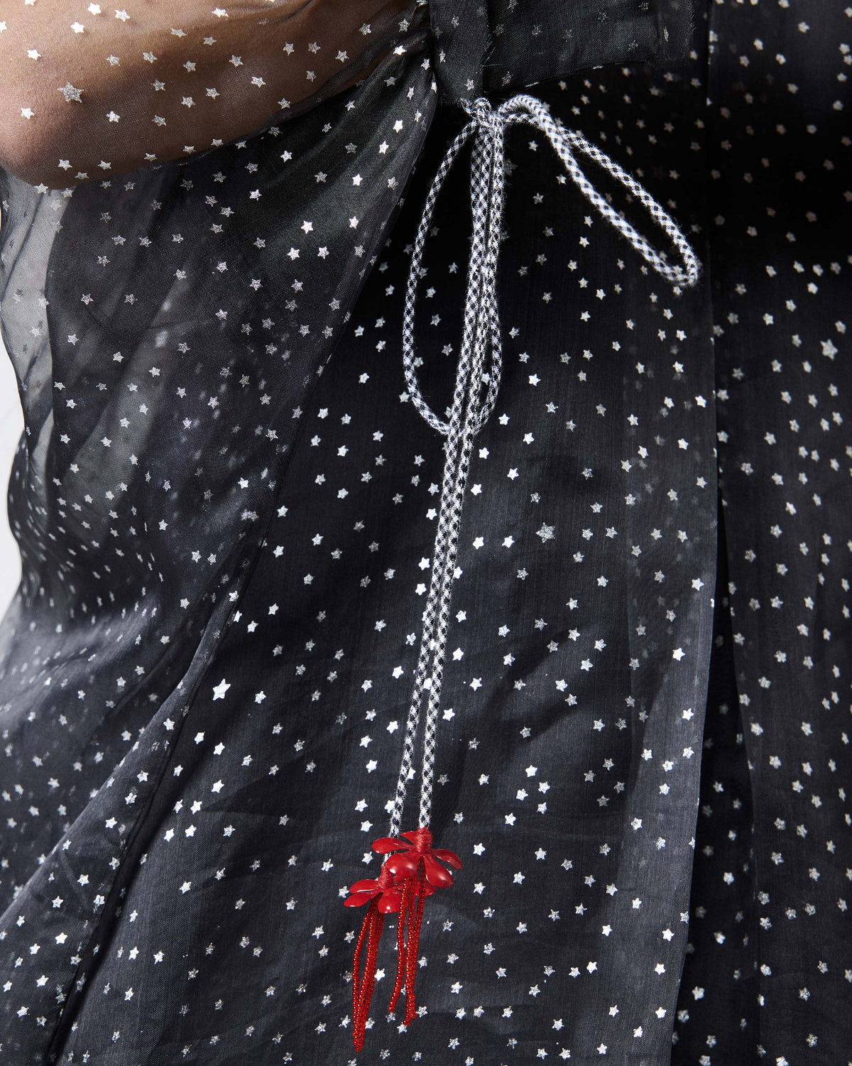 Close-up of foiled stars and red tassels on a charcoal Amboli Kaftan.