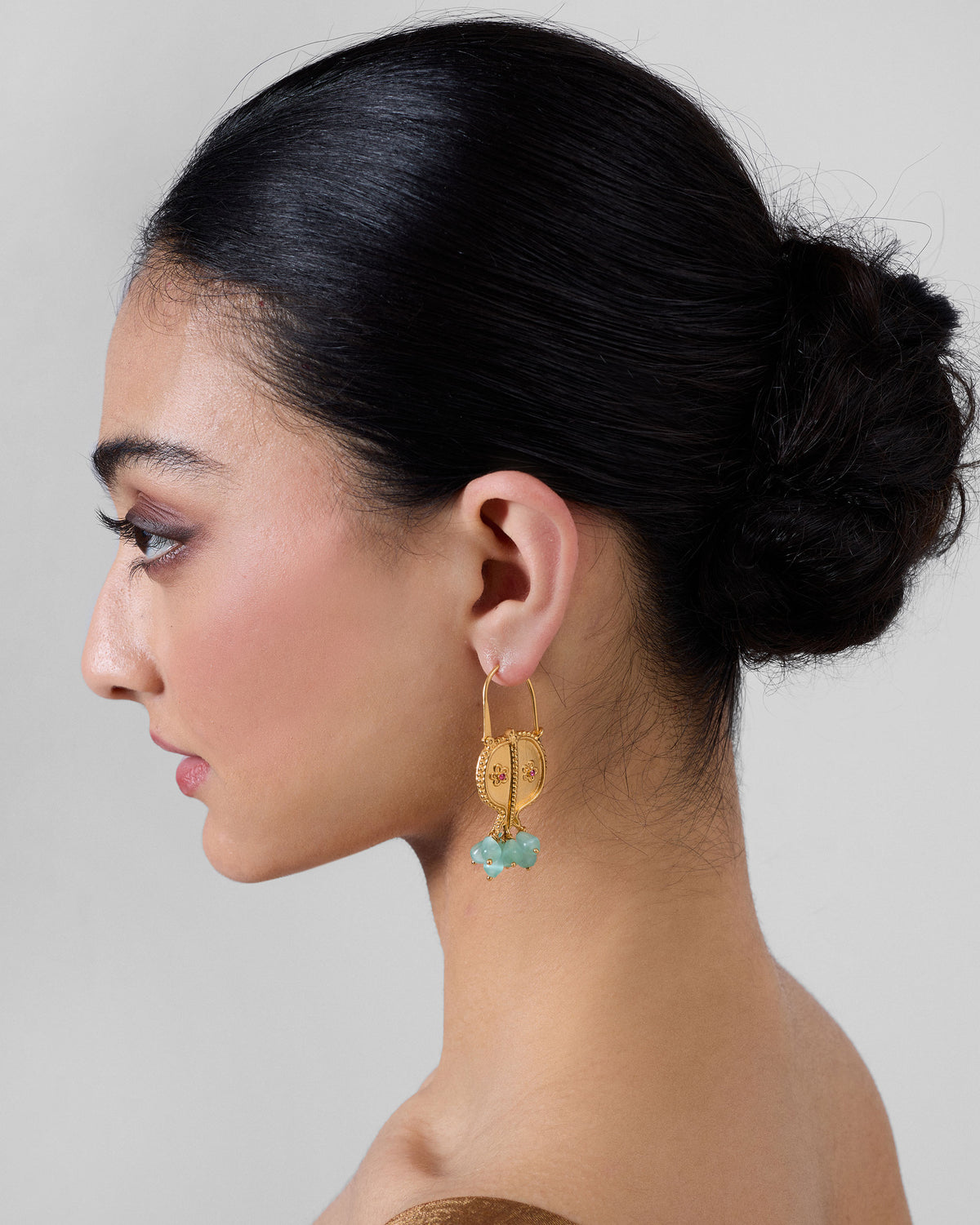 Side profile of gold Anaar balis with pale green bead drops on a person.