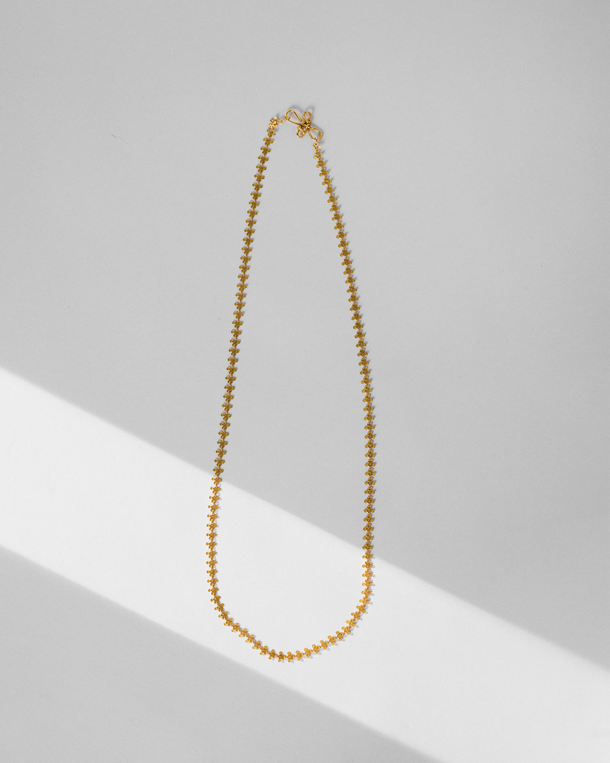 Long gold Milni necklace with repeating floral links.