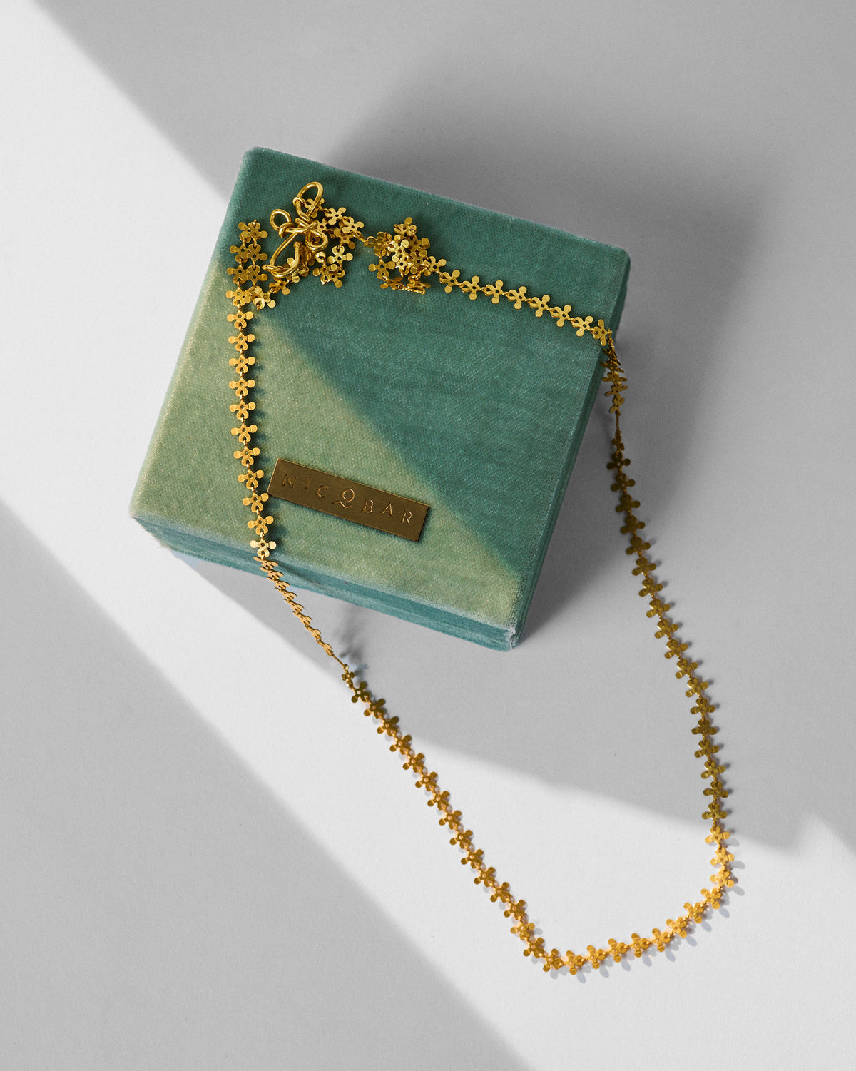 Gold Milni necklace draped over a teal Nicobar gift box.