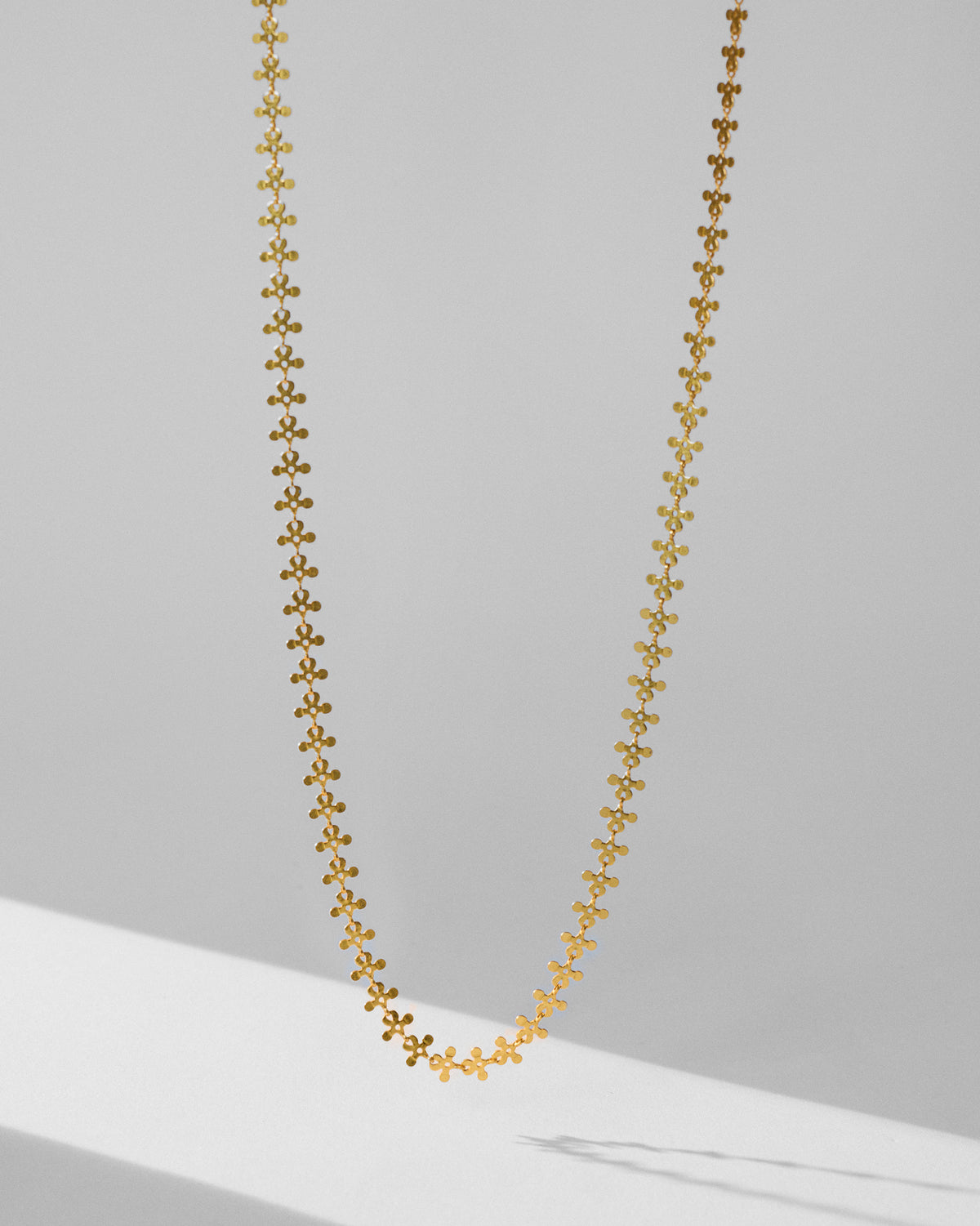 Gold Milni necklace with a continuous floral link chain.