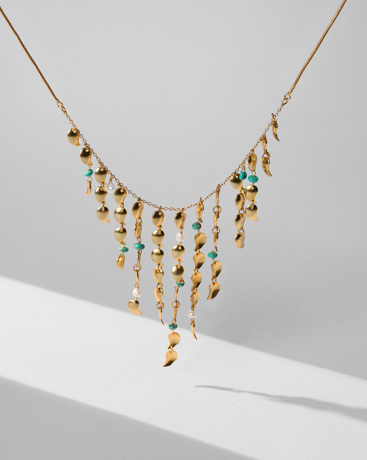 Gold Kairi necklace hanging to show graduated mango-charm fringe.