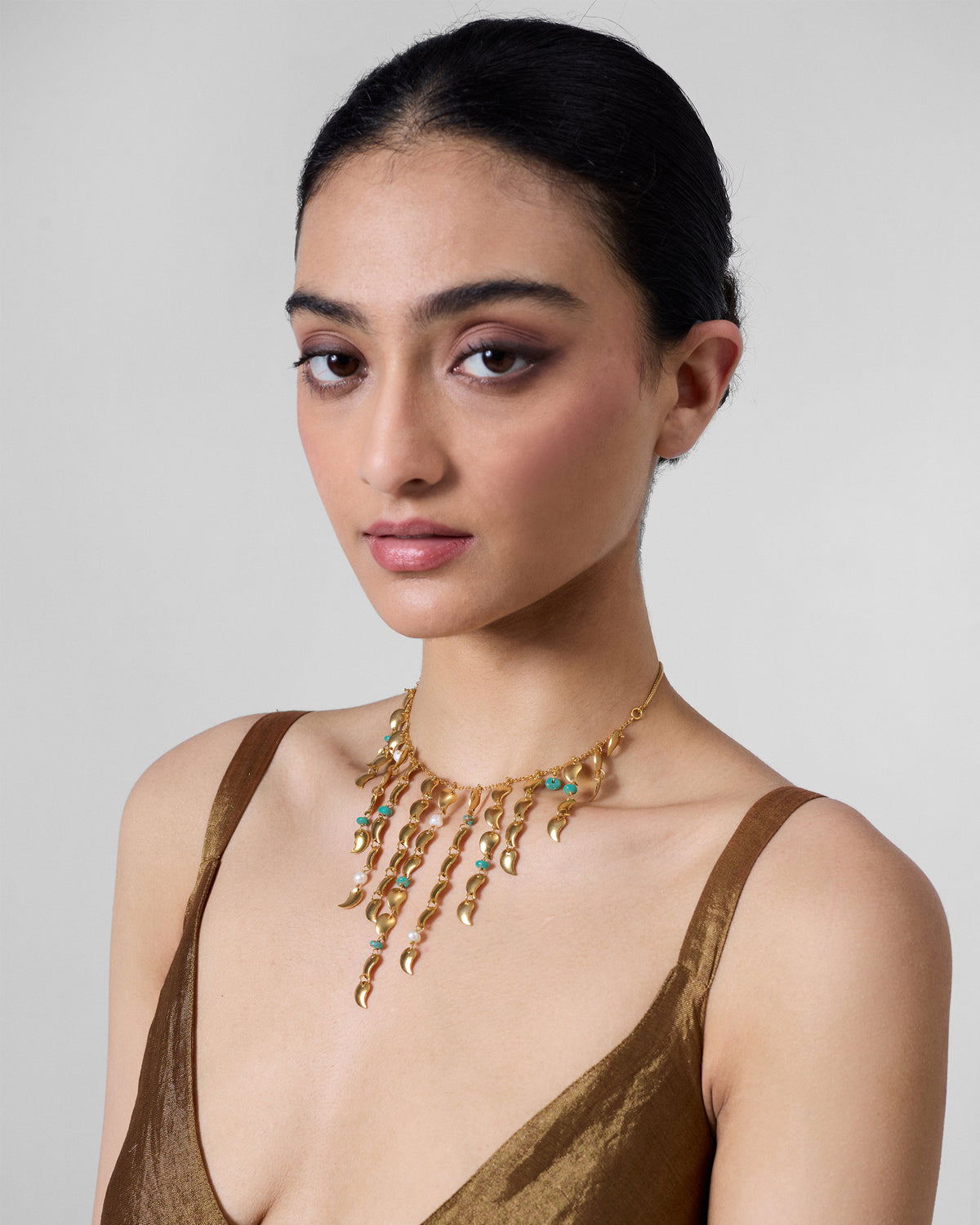 Person wearing a gold Kairi fringe necklace with turquoise bead accents.