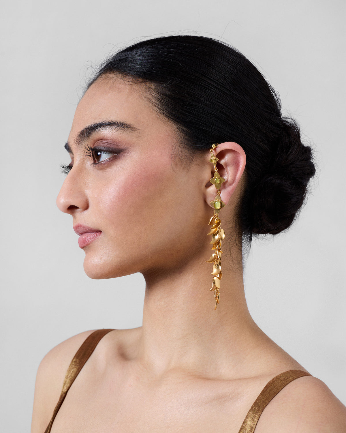 Side view of a person wearing a Kairi Earring with curved gold drops.