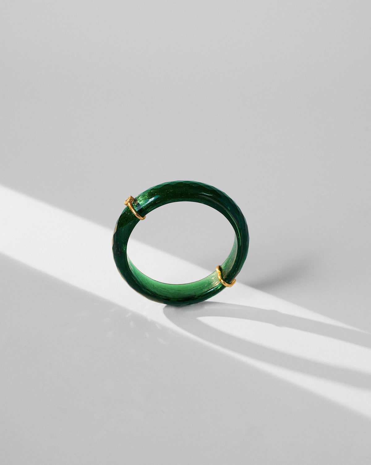 Green glass dhoop bangle standing upright showing its translucency.