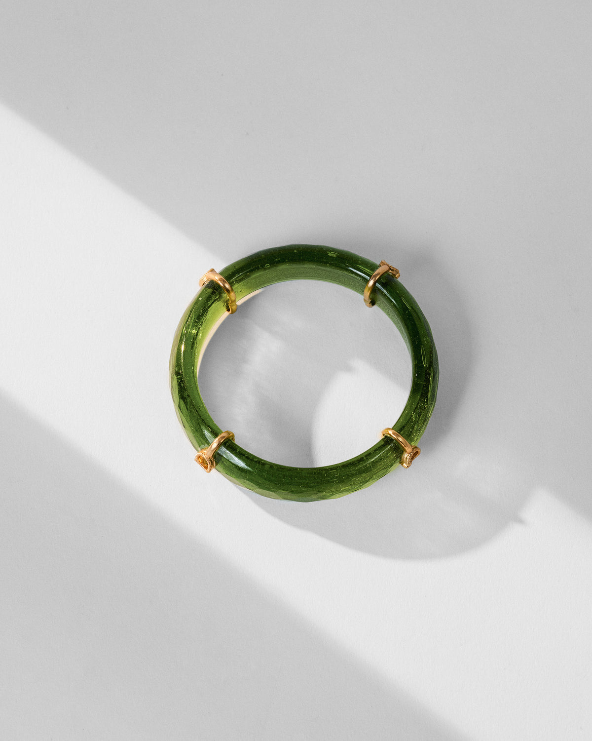 Translucent green Ambi bangle with spaced gold ring accents.