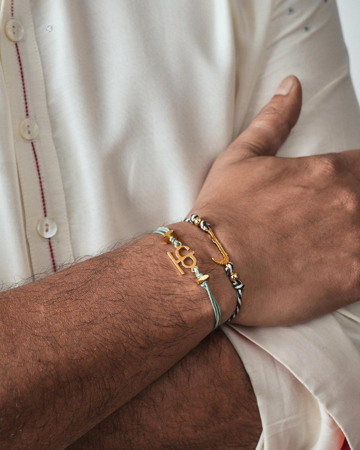 Person wearing Croc Rakhi on the wrist, stacked beside a light blue bracelet.