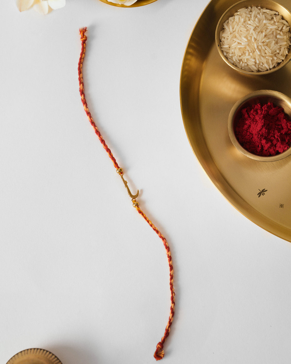 Red Croc Rakhi laid flat with a gold charm on the cord.