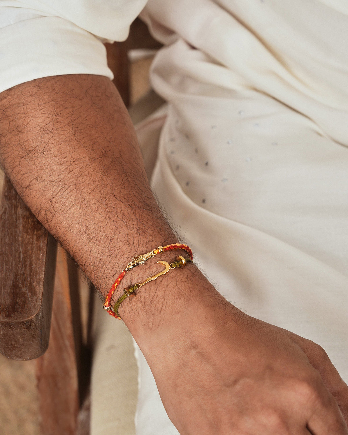 Gold charm rakhis worn stacked on a wrist.