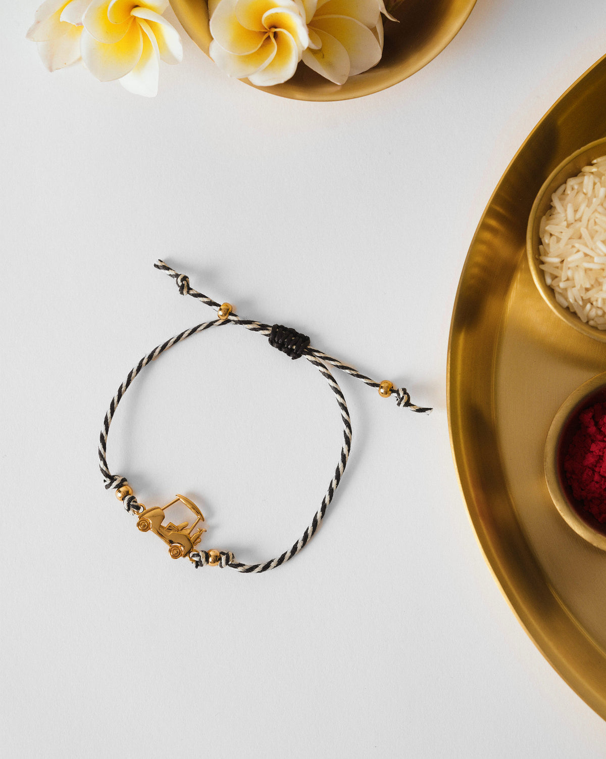 Golf Cart Rakhi in black and white thread laid flat on a white surface.