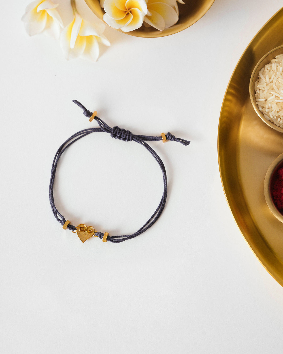Blue Dil Rakhi with a gold heart charm laid flat.