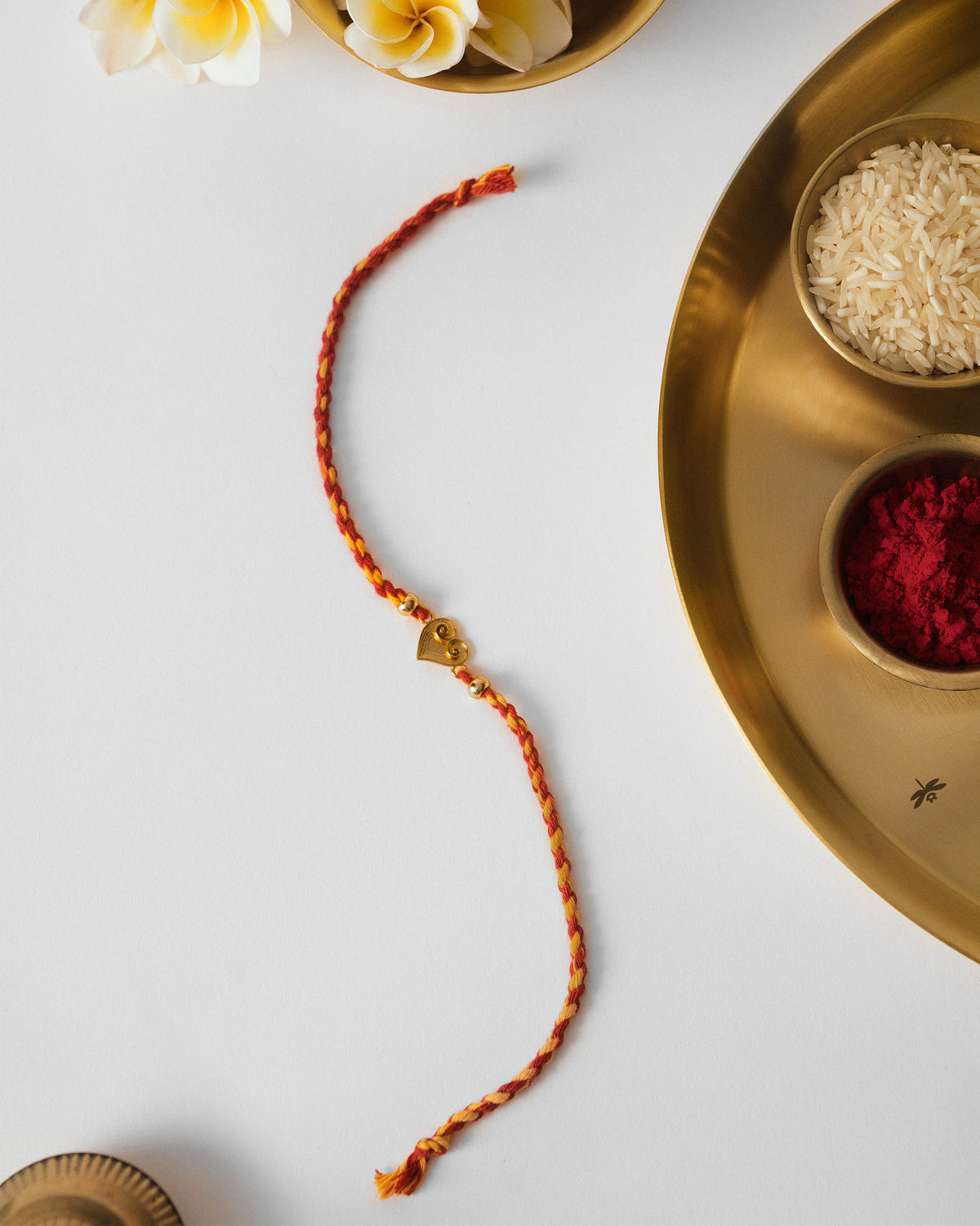 Dil Rakhi in red braided thread with a small heart charm.
