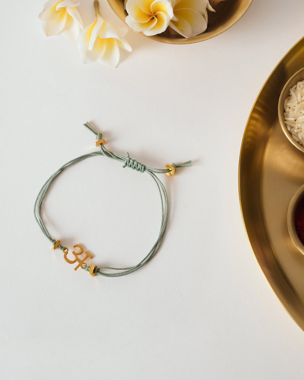 Aqua cotton alphabet rakhi with a gold-plated letter charm and gold beads.