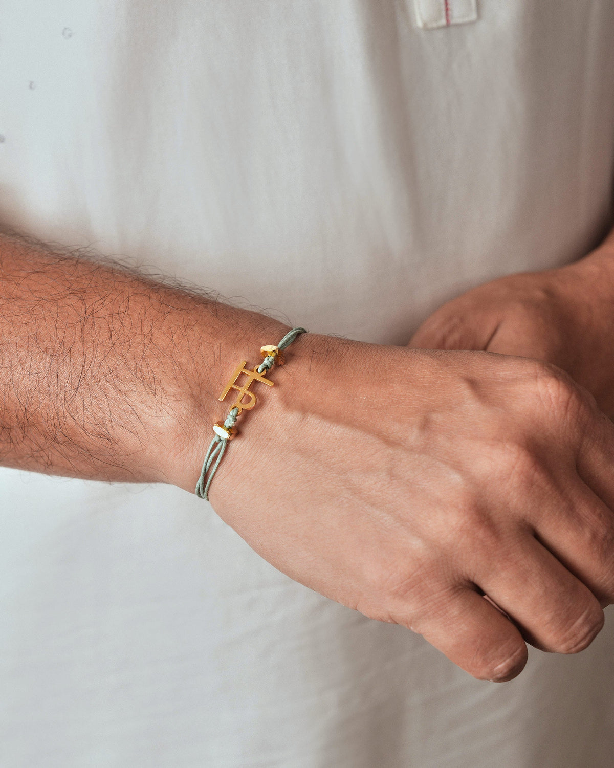 Alphabet M rakhi with a gold letter charm worn on a wrist.