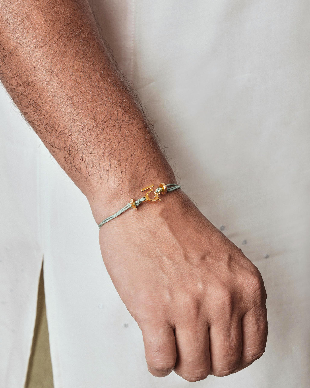 Person wearing Alphabet D Rakhi with a gold charm on the wrist.