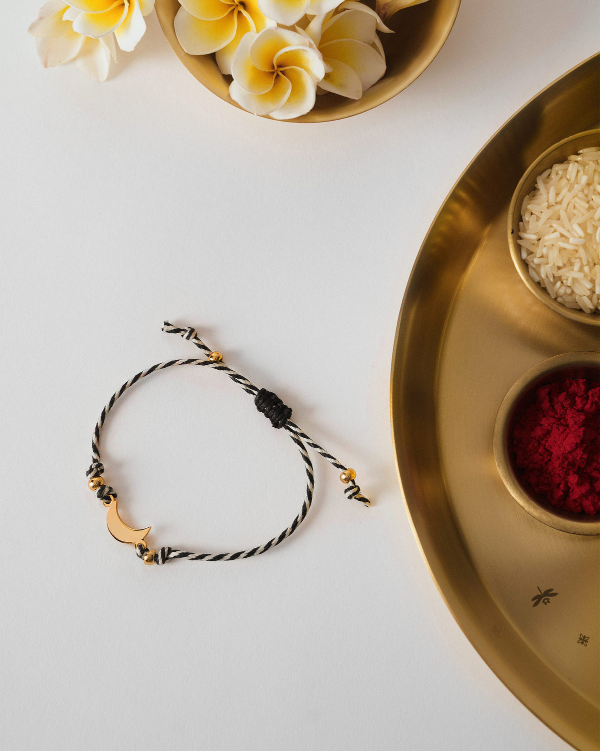 Chand Rakhi laid flat with a gold crescent charm.